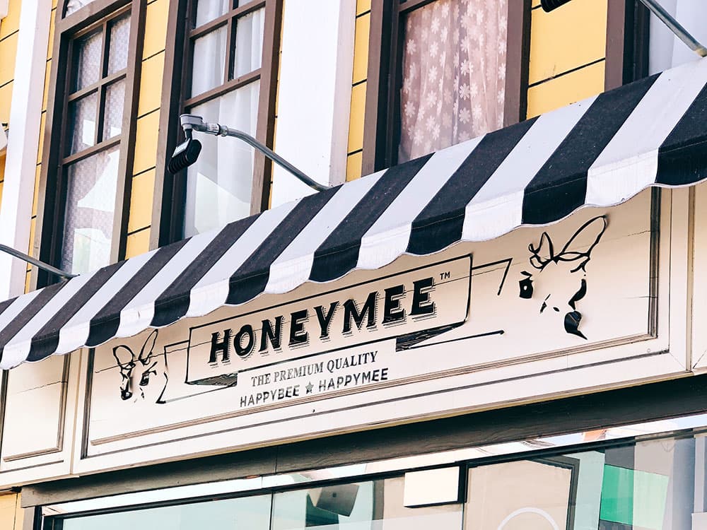 Honeymee storefront with striped awning and hand-drawn bee sign